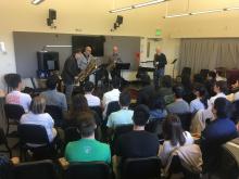 Guest presenters play music in front of students.
