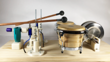 Percussion instruments mounted on a wooden plate.