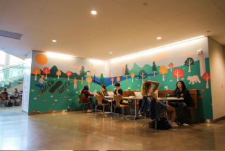 Students studying beside a mural behind them.
