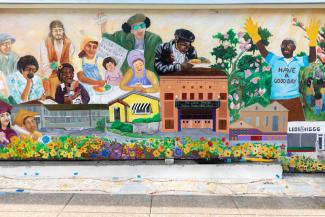 A colorful mural depicting people of color eating and growing food.