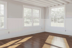 Room with wood floors, white finish on walls, and windows letting in daylight