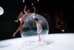 Person walking inside of a large bubble, and another person riding on top. 